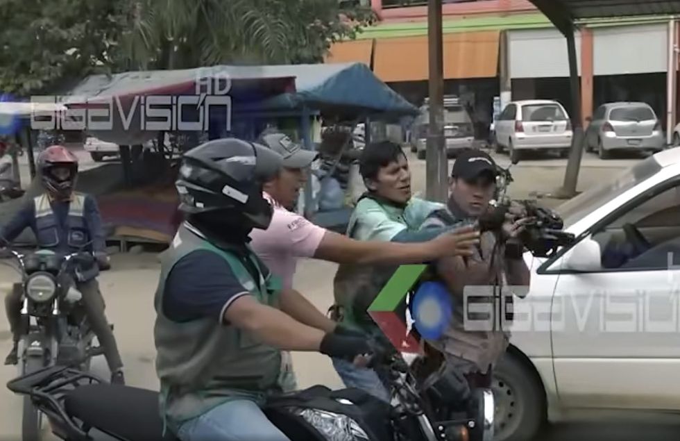 La imagen muestra el momento en que un mototaxista y un ciudadano de Villa Yapacaní intentan arrebatar una cámara a un reportero de televisión.