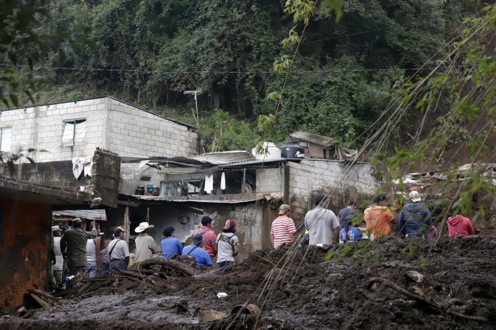 Personas observan una zona afectada por las fuertes lluvias este domingo, en Huauchinango (México).